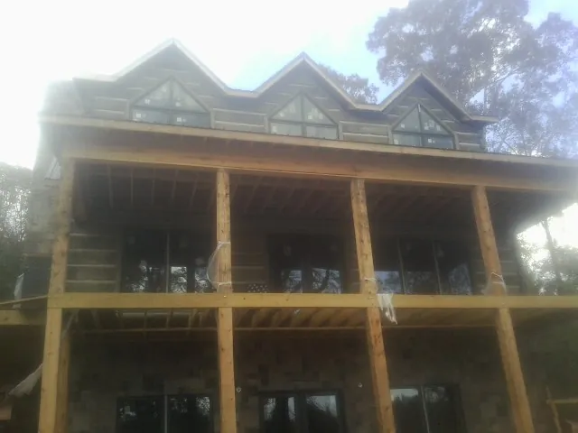 Dormers and porch framing on a large log home under construction — Roof Coating work by our crew in Williston Park