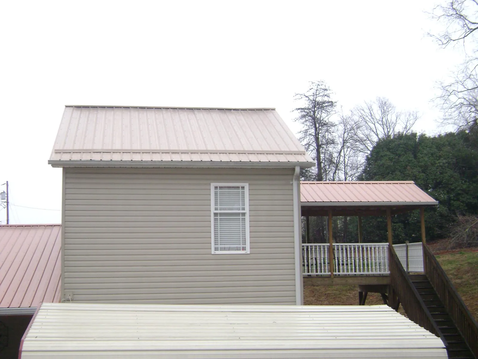Tan metal roofs on a two story addition and attached porch, from a Roof Replacement job in Williston Park