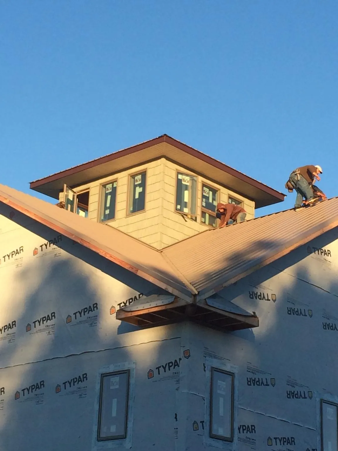 Roofers working around a rooftop cupola on a new metal roof at sunset — Roof Waterproofing in Williston Park by Roofing Brothers